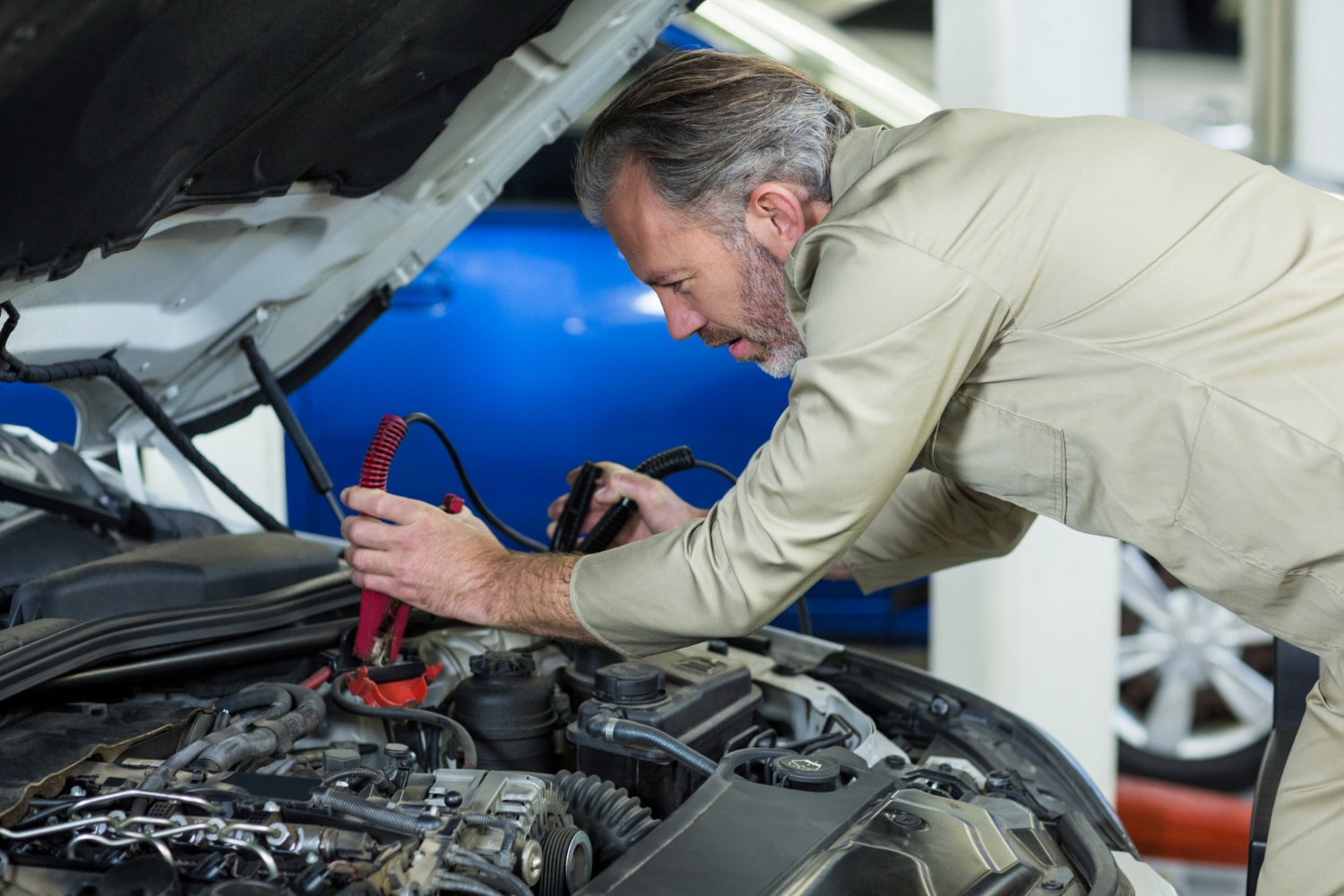 Mechanic testing a car battery using diagnostic equipment.